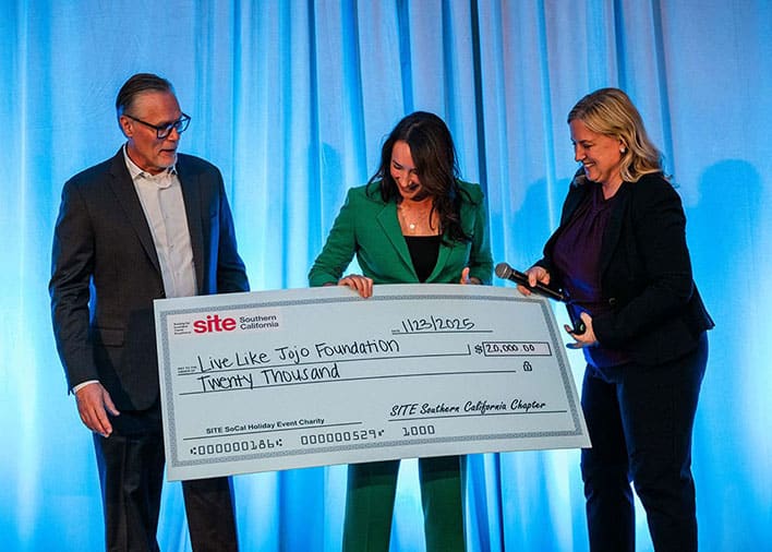 Three people stand on stage holding an oversized check for $20,000 made out to the Live Like Jojo Foundation from SITE Southern California Chapter.