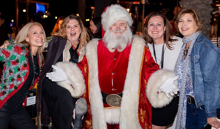 Four adult women pose together with Santa Clause and smile for a group photo at the 2024 SITE SoCal Holiday Event & Charity Gala..