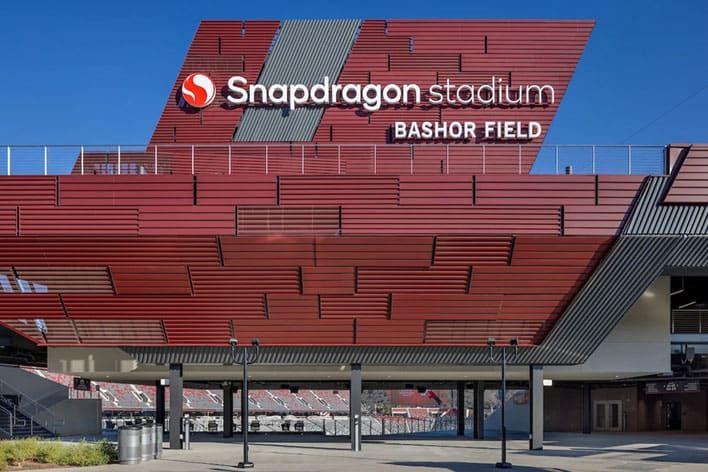 Red exterior of Snapdragon Stadium with "Snapdragon Stadium Bashor Field" signage prominently displayed above entryway.