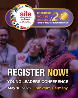 People standing and smiling at an indoor event with a banner promoting the Young Leaders Conference on May 18, 2026, in Frankfurt, Germany.