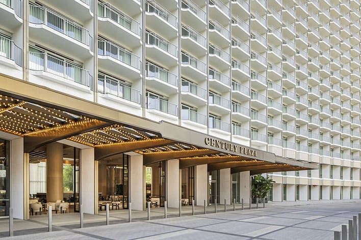 A modern, multi-story hotel entrance labeled "Century Plaza," with balconies on each floor and a covered driveway.